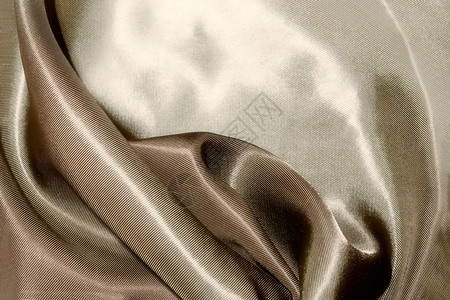 肉欲闪亮而的米色丝绸织物布满波浪的背景蜜色丝绸窗帘闪发光的图片