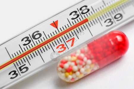 红色温度计退烧药极好的一个显示高温玻璃度计和一个药片旁边是超级大镜头背景