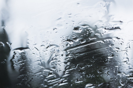 雨季期间在玻璃上的雨滴湿天纹理图片