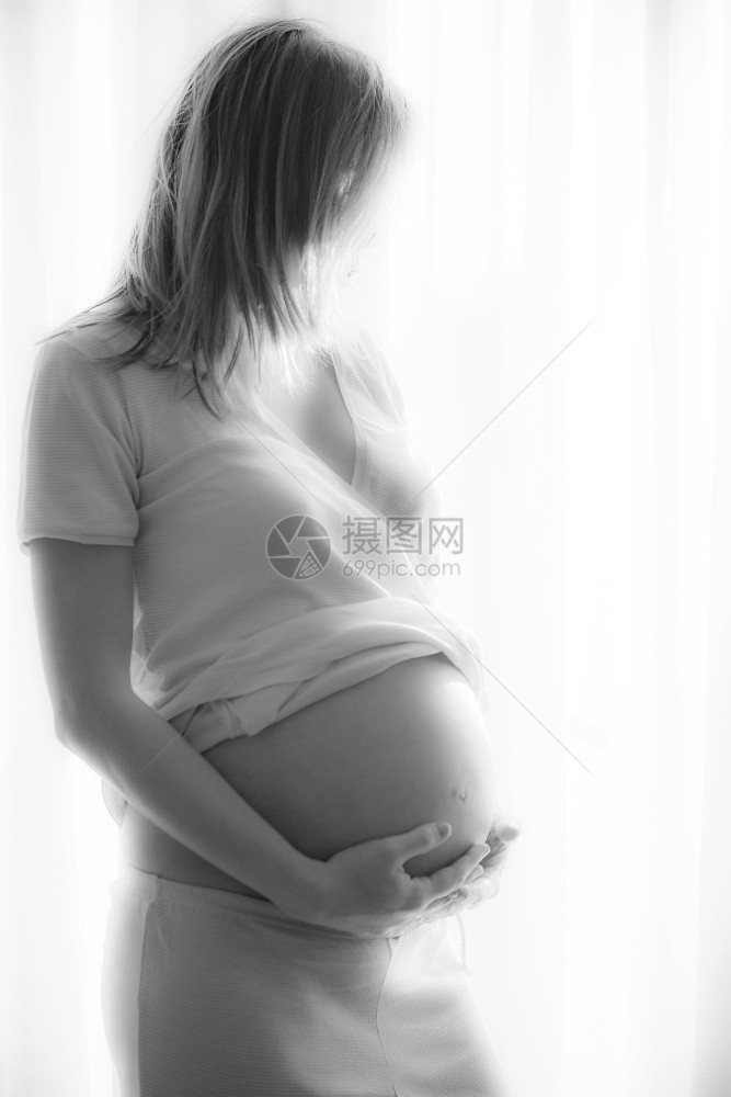 期待女士出生窗边的孕妇用手支撑子宫在窗户处的孕妇图片