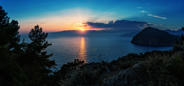 山树日落时的海湾从悬崖到日落时的海湾旅行孤独与和谐的概念水图片