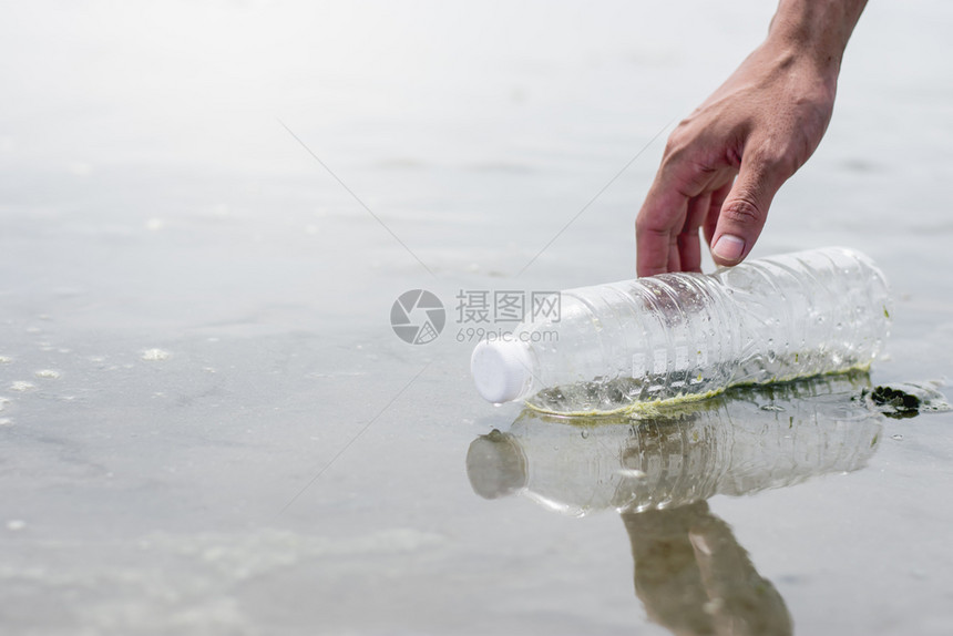 沙滩上漂浮的塑料水瓶当月经人手举起双时海边肮脏滩的概念回收环境海洋图片
