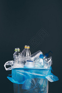 塑料瓶杯袋的堆积收集以在金属桶中回收利用的塑料瓶袋子污染概念废物过多旧塑料垃圾用包装纸裹在深蓝色背景上顶部有复制空间黑暗的处理环图片