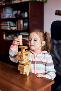 小女孩学龄前幼童玩木砖具建造一座塔构筑房子的概念童年教育游戏图片
