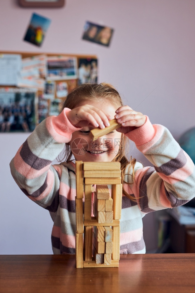 创造力堵塞家小女孩学龄前幼童玩木砖具建造一座塔构筑房子的概念图片