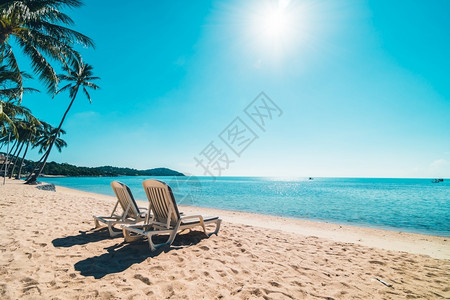 天堂晴美丽的热带海滩和在蓝色天空上坐椅子旅行和度假伞图片