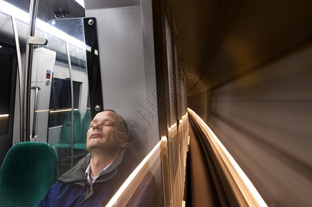 独自的窗户晚男人睡在快速移动的地铁里在深夜骑车回家图片