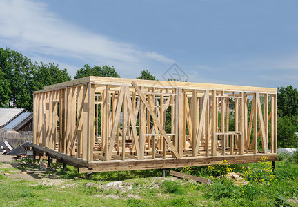 分区家木制的堆积地架和隔板上正在建造的木房屋框架图片