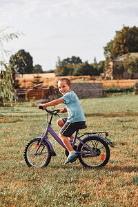 玩一种骑术快乐笑的男孩骑自行车学习在家庭花园里生活的人真实情况图片