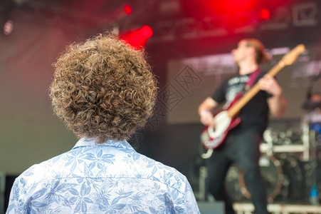 吉他发型长着卷的年轻人在舞台上看摇滚乐队居住图片