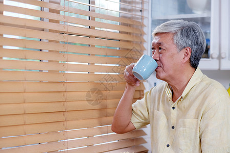 老人在家庭背景的厨房里站在喝咖啡时的人们生活方式尽管肖像随意的图片