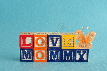 教育爱的妈用字母块拼写的词用橙蝴蝶在蓝色背景上拼写的木头图片