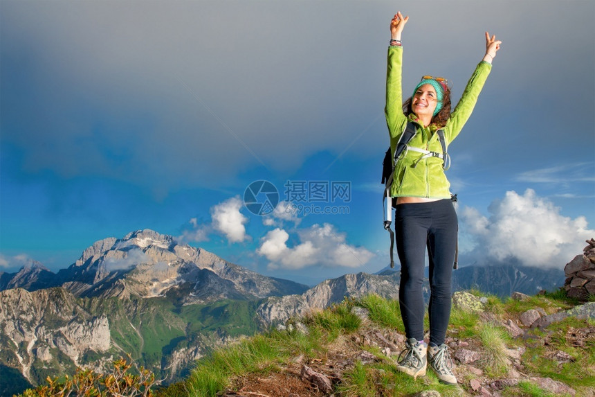 年轻的天空最佳女孩在山顶的峰上举起她的双臂快乐图片