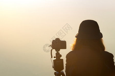 旅游户外女孩摄影师在清晨时等待着用雾景拍摄地貌照片图片