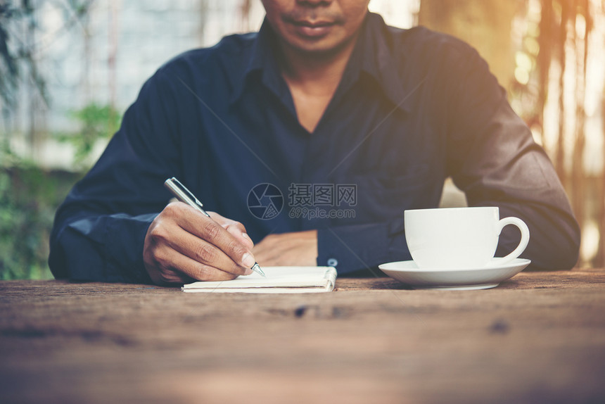 在质朴的木桌上工作笔记本写字年轻人在质朴的木桌上工作笔记本写字年轻人桌子乡村一种图片