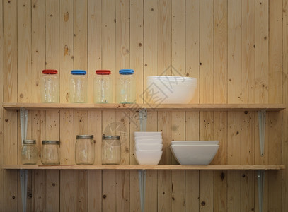 架子排厨房用木墙背景的碗和罐子套架家图片