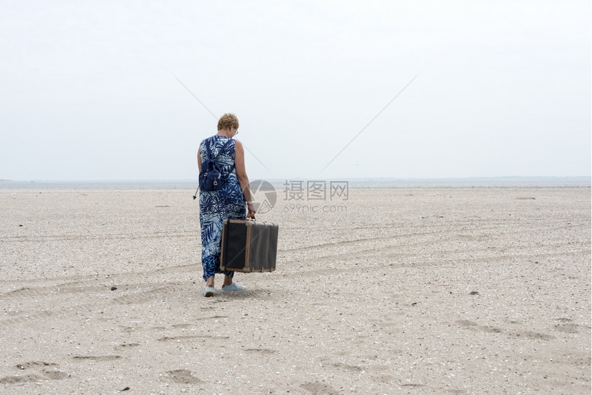 包步行在海滩附近走的旧古老妇女用手提箱靠近图片