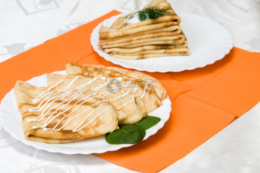 一堆俄罗斯煎饼在白色盘子上奶油香菜俄语图片