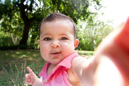 可爱的婴儿快乐伸出手臂就像她在公园拍自肖像照片一样摄影有趣的种图片
