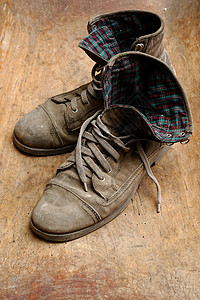 染色脚丫子旧皮鞋对等破和灰色的皮鞋木制背景的旧皮鞋对等斯克莱兹涅夫图片