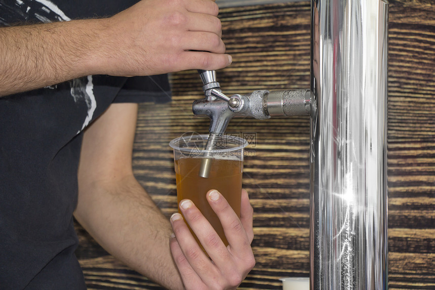 酒吧用轻啤装满塑料玻璃杯的男士控制商业图片