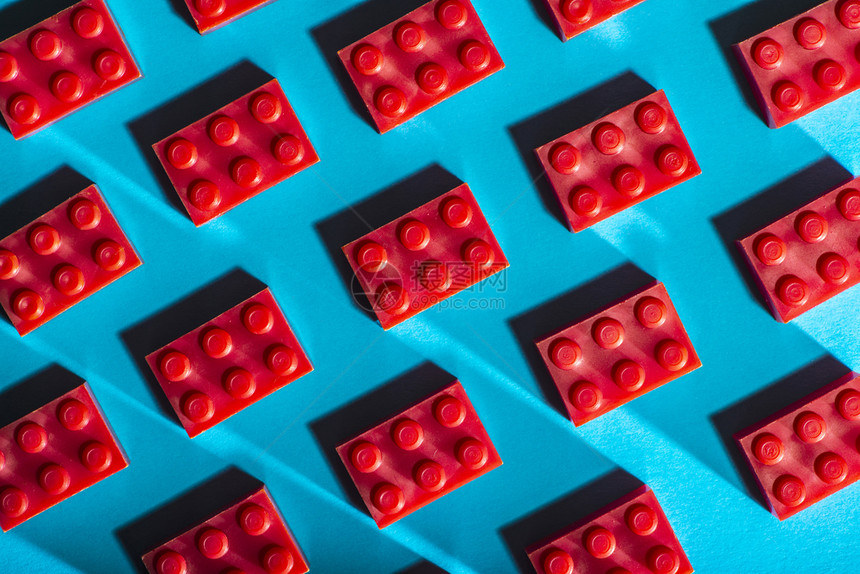 对比鲜明游戏学习红塑料几何立方对比蓝底面的红塑料几何立方体在形状上建造玩具安装在行内排列的几何形状上在塑料砖布设的图片