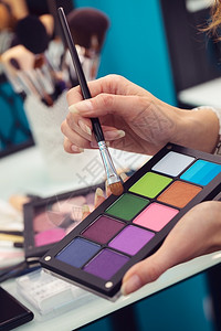 化妆艺术家拿着彩色双眼草和刷子的调色盘关上制作粉末心图片