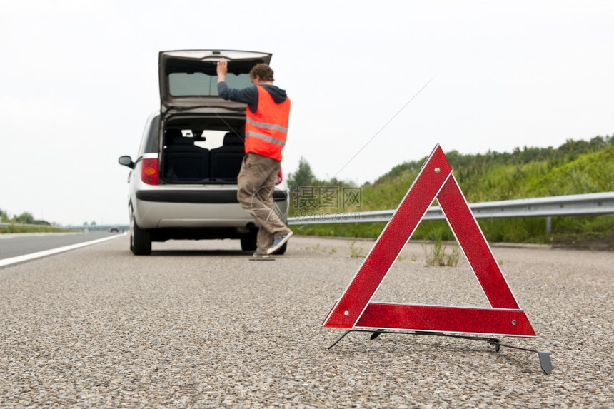 抑制车辆旅行警示三角形在一辆破烂的汽车后面门帽在高速公路紧急通道上打开图片