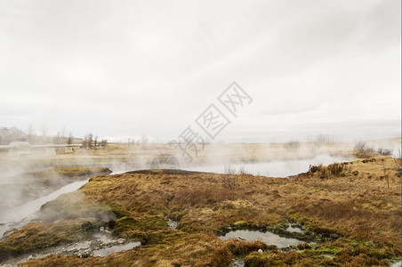蒸着活力量带雾云和棕草的冰地热泉图片