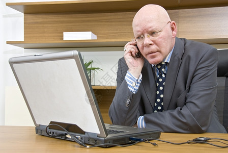 商业老板正面一名公司经理坐在笔记本电脑前在移动话上说a一名公司经理图片