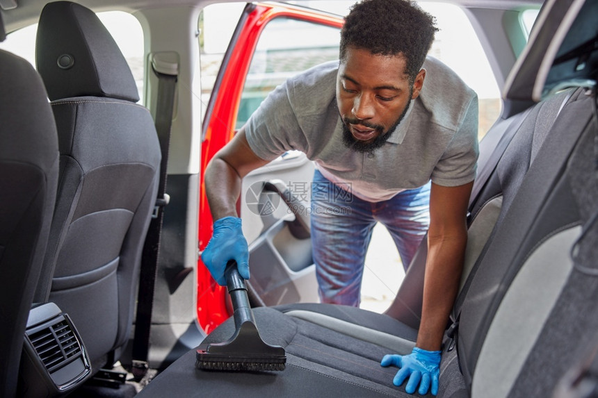 干净的美国人在汽车代售期间男子漫游和清洁车后座内部的图片