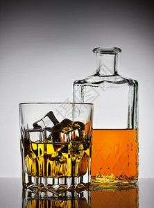 刻面坡度相杯威士忌冰和瓶子在梯度背景上优雅图片