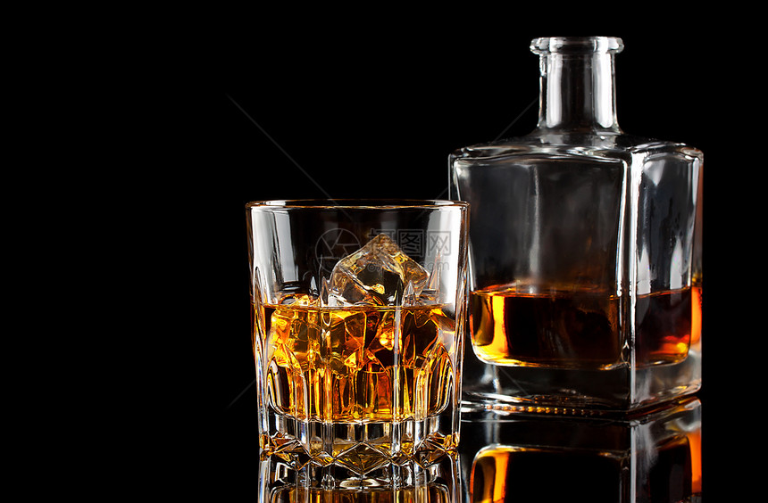 威士忌酒一杯加冰和一平方脱石孤立在黑色背景上暗的鸡尾酒图片
