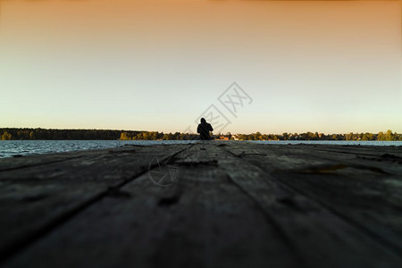 海洋在橙色日落码头的孤人年轻图片