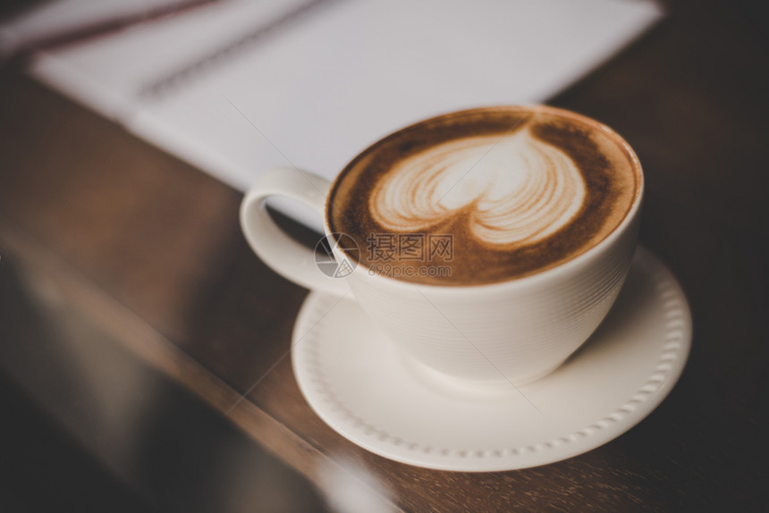 牛奶热咖啡拿铁艺术的古老音调以心形装成的热咖啡拿铁艺术在茶桌上的杯子喝着热咖啡拿铁艺术的旧音调颜色泡沫图片