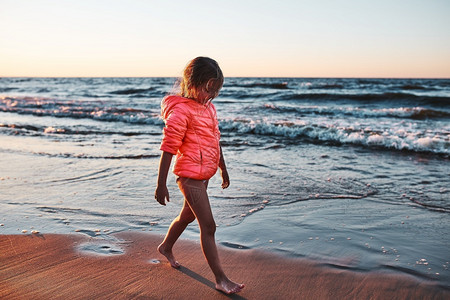 步行乐趣女孩在暑假日落时赤脚在海滩上走小女孩在日落时赤脚海滩上走喜悦图片