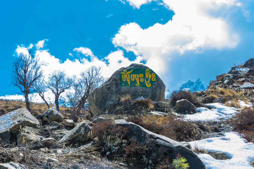 咒语题词尼泊尔山上的石头有彩色碑文在日出之一种图片
