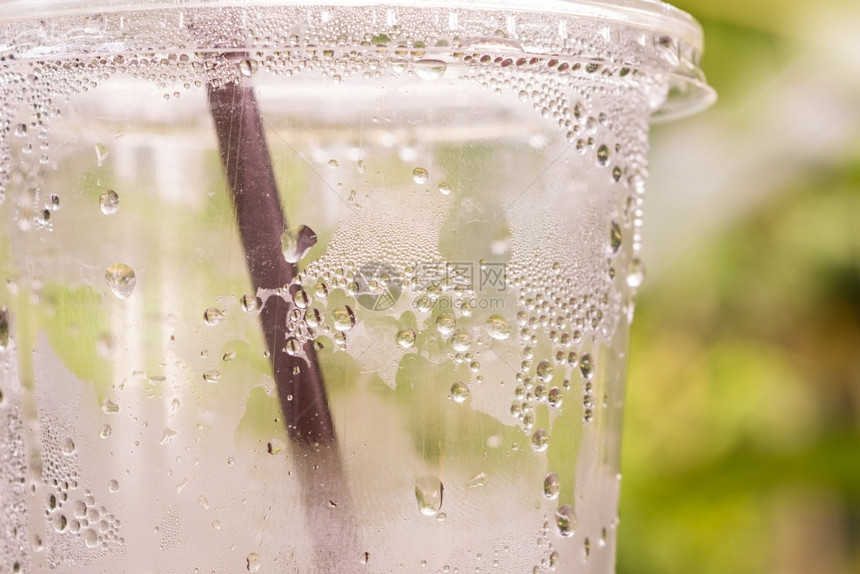 水滴流动有绿色背景的塑料饮瓶上滴水的以绿色背景为白色的图片