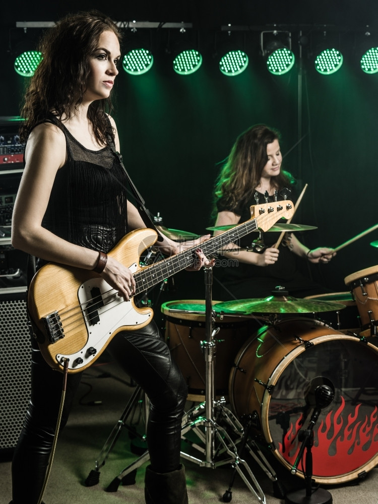 一位女吉他手和摇滚乐队在舞台上演奏的照片图片