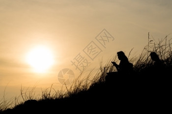 晚上太阳落下时坐在山坡上的人休丽月光女孩橙下降图片