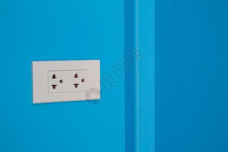蓝色的电气在涂漆蓝色水泥墙上安装的白色电源角落图片