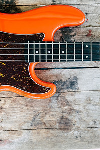 歌曲木背景和复制空间的橙色电贝须吉他的手图片