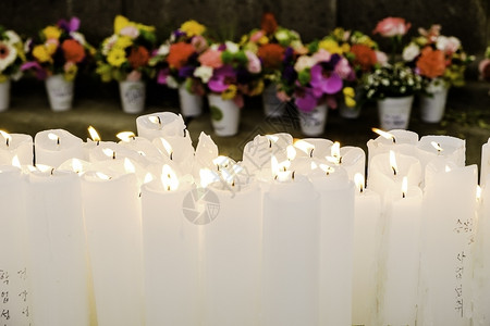 在佛教寺庙的祭坛上燃烧着一串白蜡烛在幕后布置鲜花供奉人们拉根火焰图片