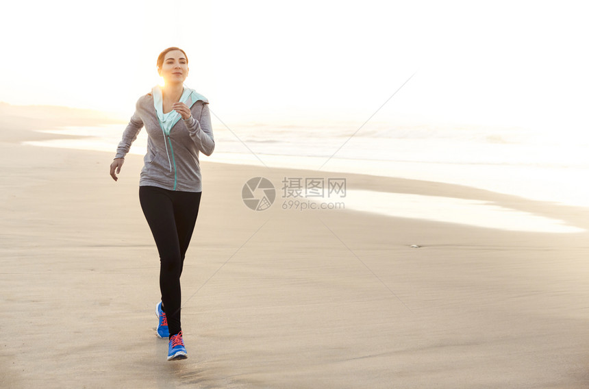 健康的女人在沙滩上奔跑图片