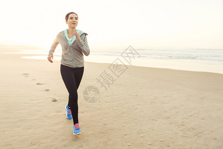健康的女人在沙滩上奔跑图片