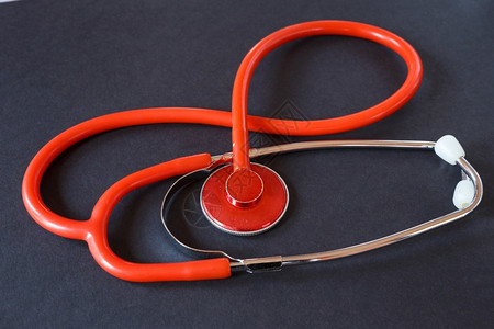 医生心脏桌子黑色背景上的红医用听诊器于收的医疗仪器图片