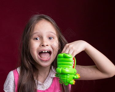 亚洲人年轻的裔美国女孩带着绿色鳄鱼玩具咬手可爱的图片