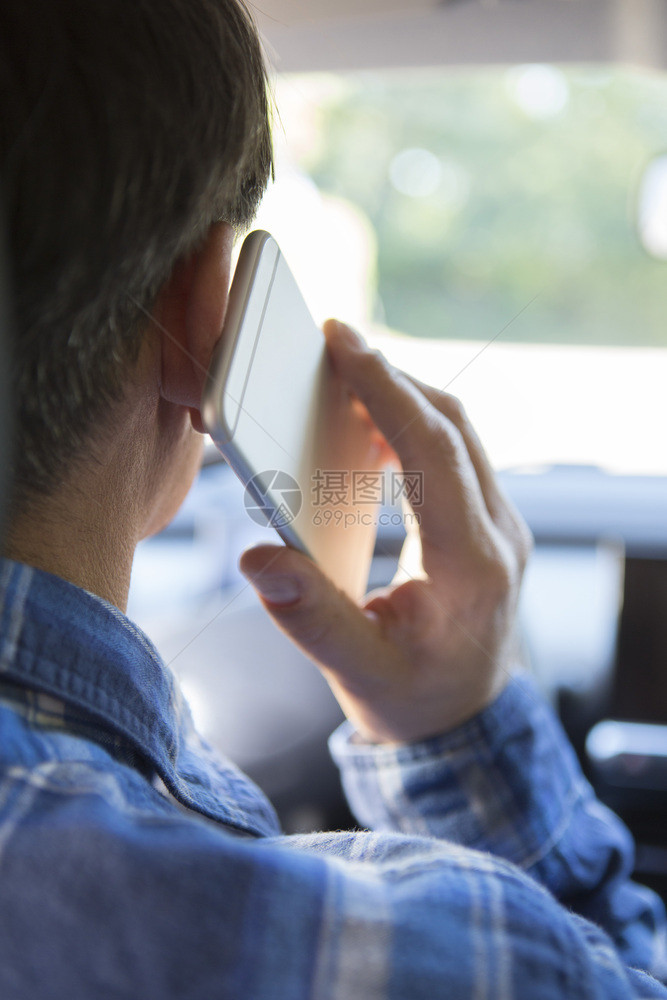 粗心在汽车里谈论移动电话时驾驶的男人分心垂直的图片
