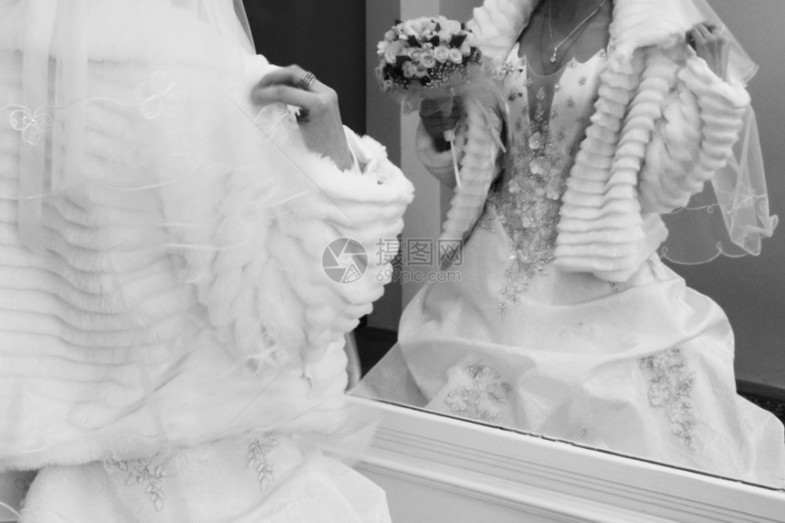 女浪漫的传统礼服和皮衣中的新娘被割成景象婚纱花束着结照镜子看着她的倒影成人图片