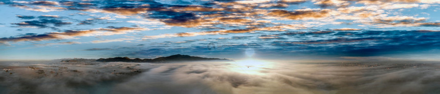 多于超过由日落时云上方无人驾驶飞机观测到的风雾环绕着农村景象的全空中观察图片